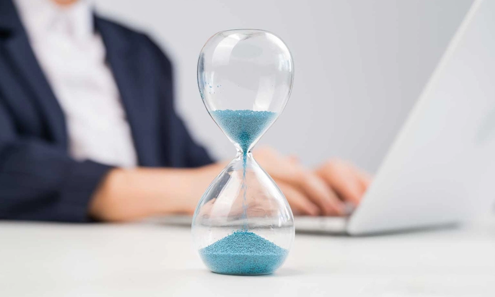 Business woman keeps track of time on an hourglass while working